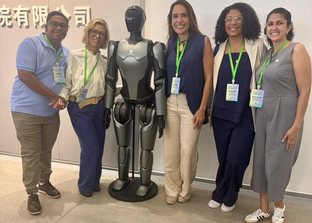 Da esquerda para a direita, Júlio César, Oneida, Lorena, Amábile e a coordenadora de Relações Internacionais, Fernanda Oliveira, com o robô humanoide